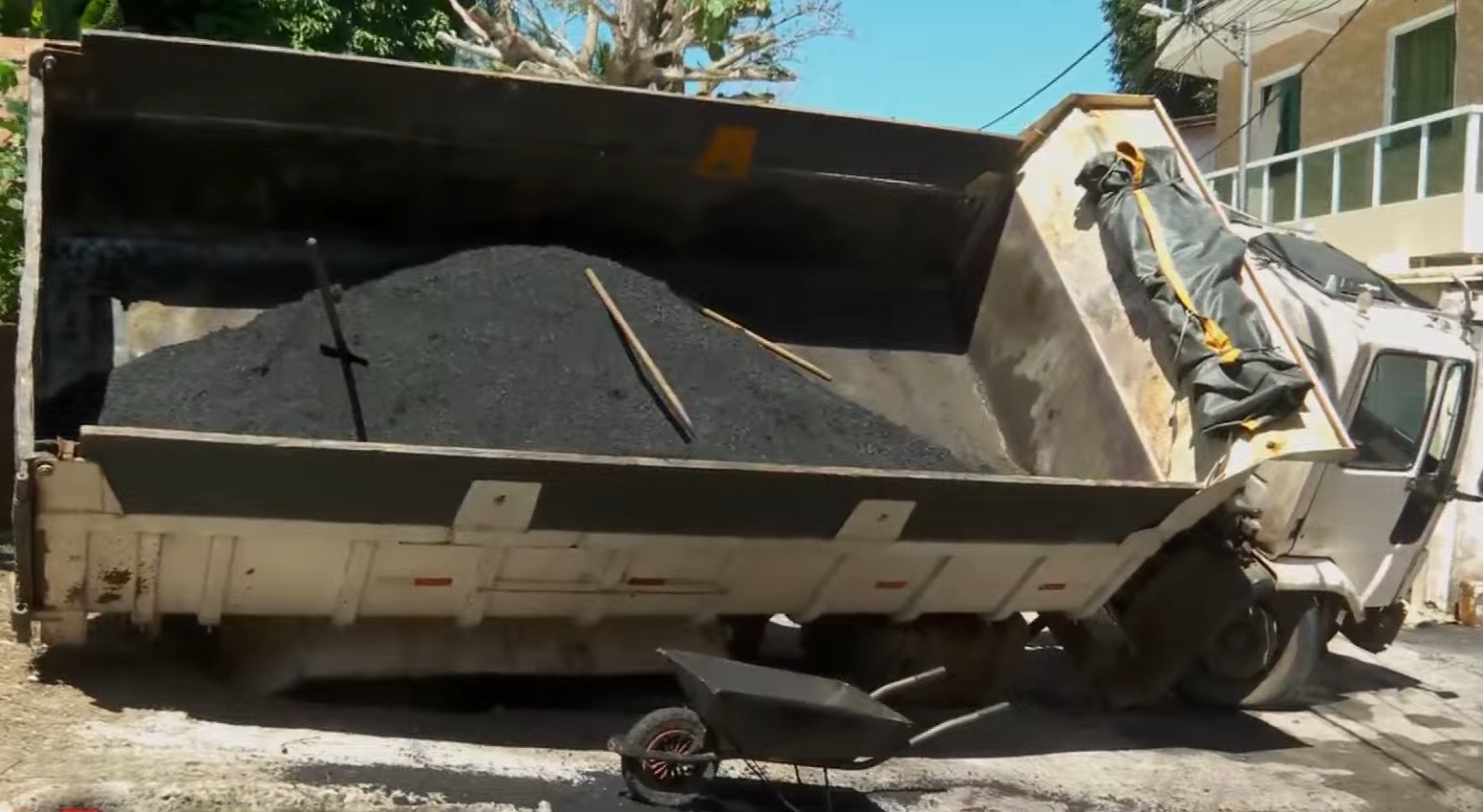 Uma ca&ccedil;amba virou ap&oacute;s o asfalto de uma rua ceder no bairro de Pernambu&eacute;s, em Salvador, no in&iacute;cio da tarde desta quinta-feira (10). | Foto: Reprodu&ccedil;&atilde;o/TV Aratu