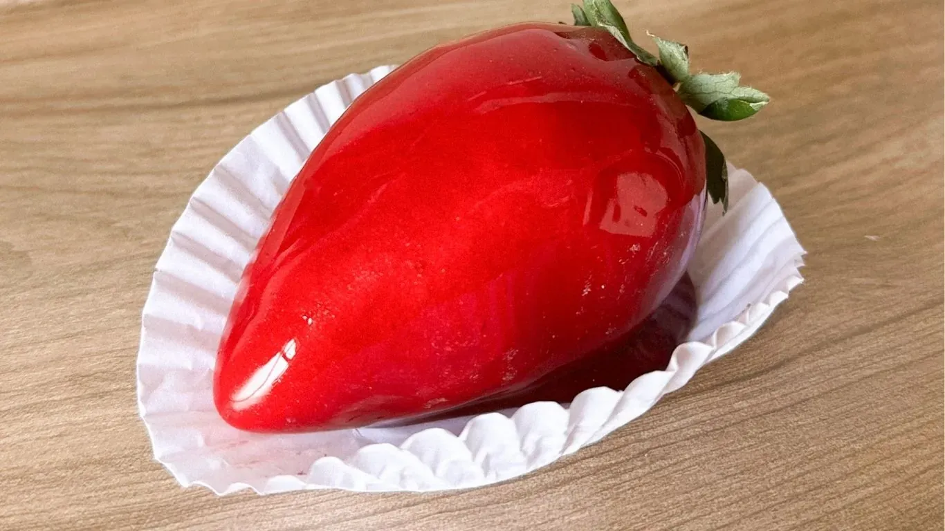 No morango do amor, a fruta &eacute; mergulhada em uma calda de caramelo com corante vermelho. | Foto: Kit Festa BH