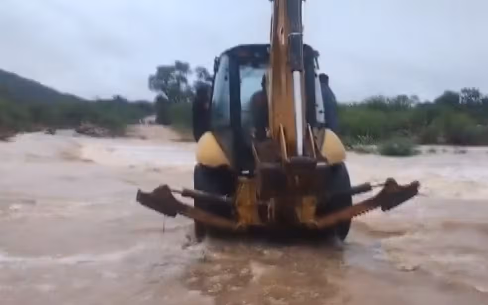 Uma moradora do povoado de Po&ccedil;o de Fora, em Cura&ccedil;&aacute;, na Bahia, precisou atravessar um rio com o aux&iacute;lio de uma retroescavadeira. | Foto: Redes Sociais